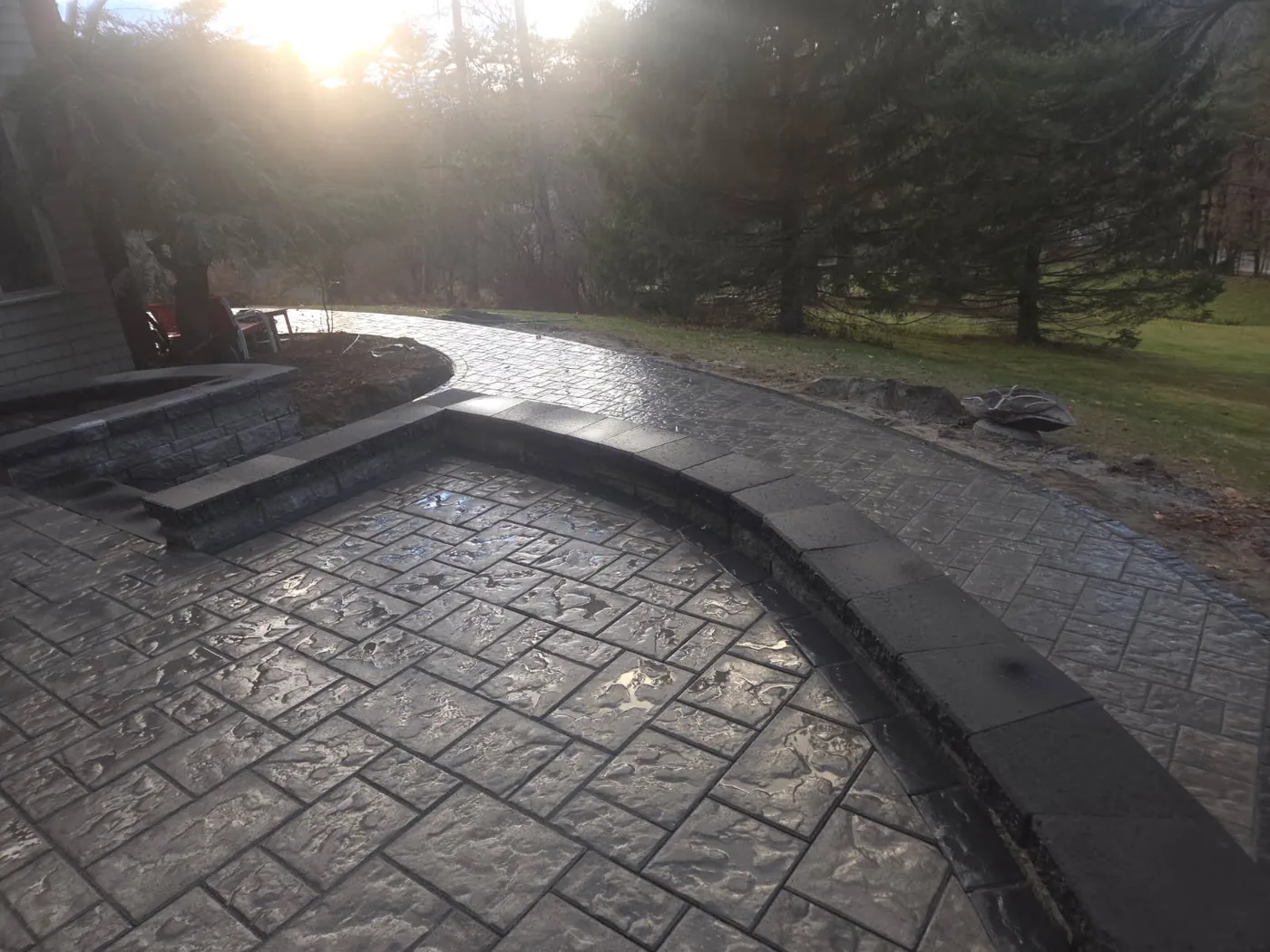 Curved stamped concrete patio edged by a dark capped block wall