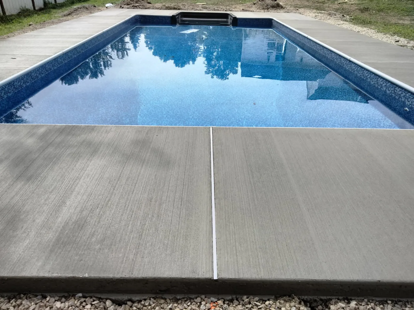 Brushed concrete pool deck with a control joint beside a rectangular pool