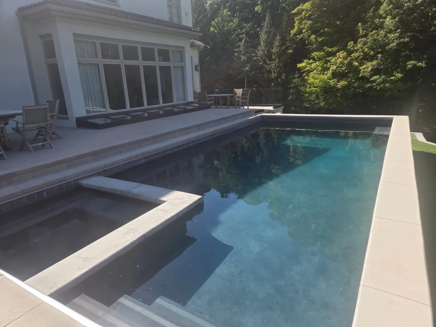 Smooth light concrete pool deck and coping around a rectangular pool